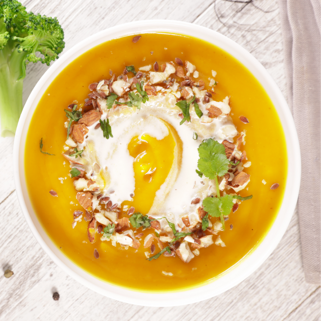 reamy butternut squash soup in a bowl with a swirl of pure culinary argan oil and fresh herbs.